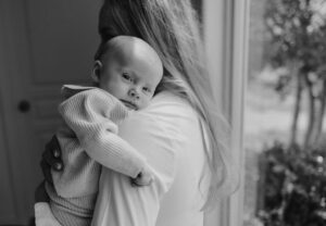 newborn by window black and white photo