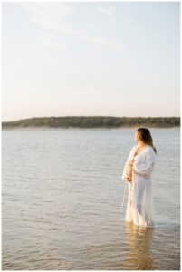 Mother holds pregnant belly for Sandy Beach Maternity Session