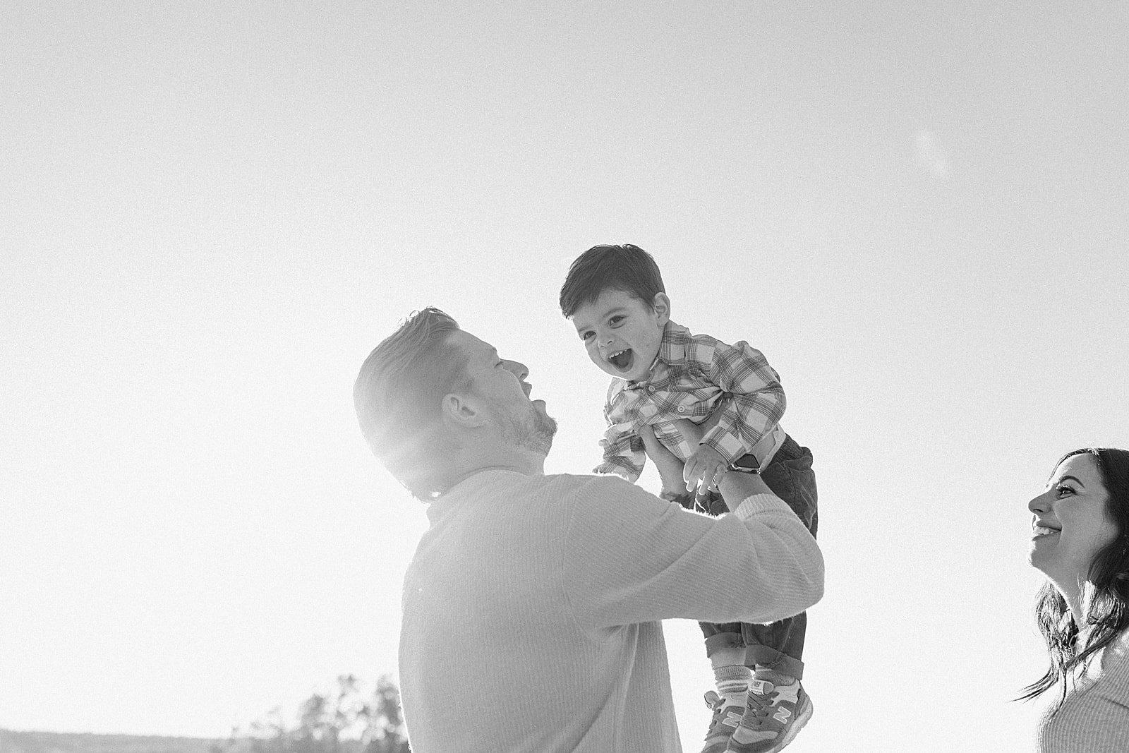 Dad lifts son in the air during an Outdoor Lifestyle Maternity Session